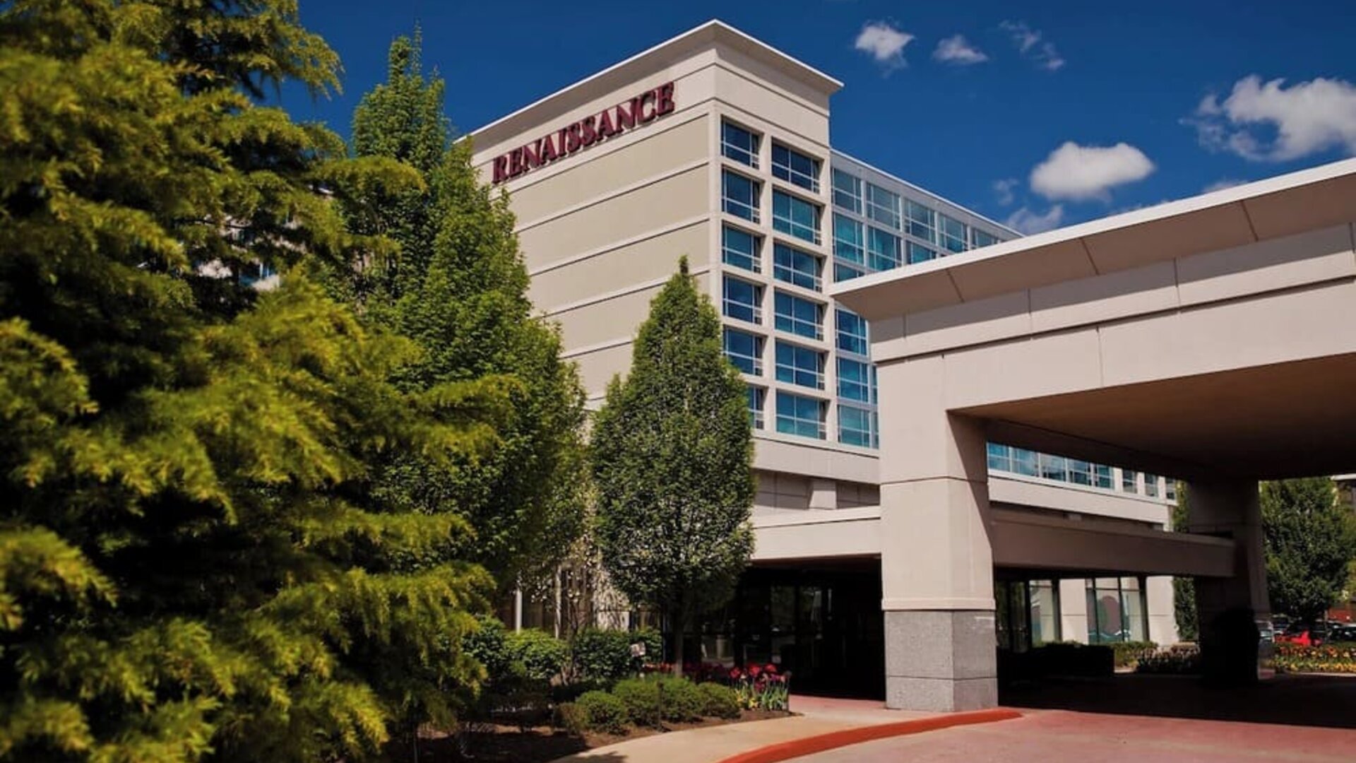 Hotel exterior with Renaissance signage, entrance canopy, trees, and driveway at Renaissance Newark Airport Hotel.