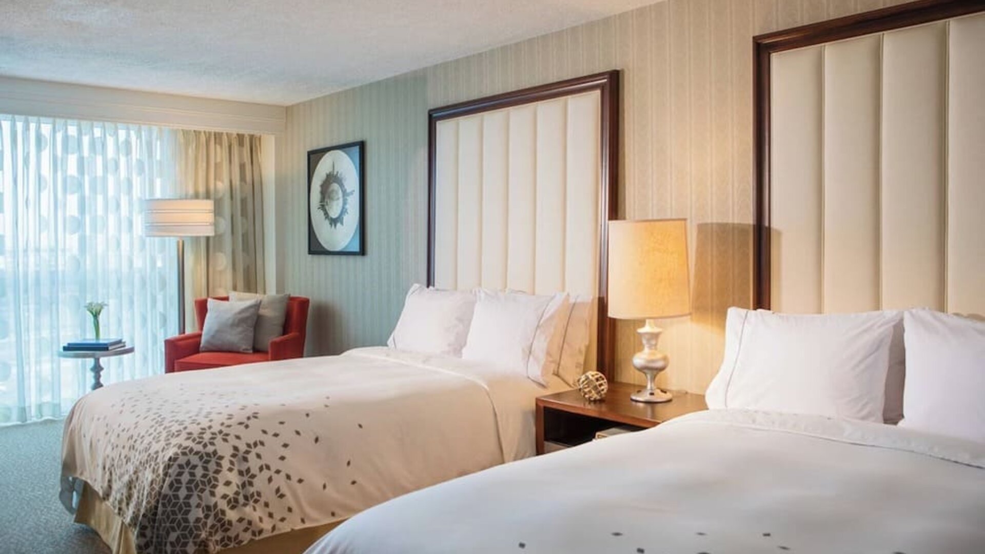 Guest room with two double beds, bedside lamp, armchair, and sheer curtains at Renaissance Newark Airport Hotel.