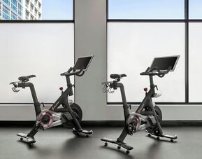 Two stationary bikes facing large windows in fitness area at Renaissance Newark Airport Hotel with city view.