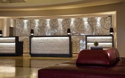 Lobby reception desks with decorative wall panels, warm lighting, and seating at Renaissance Newark Airport Hotel.