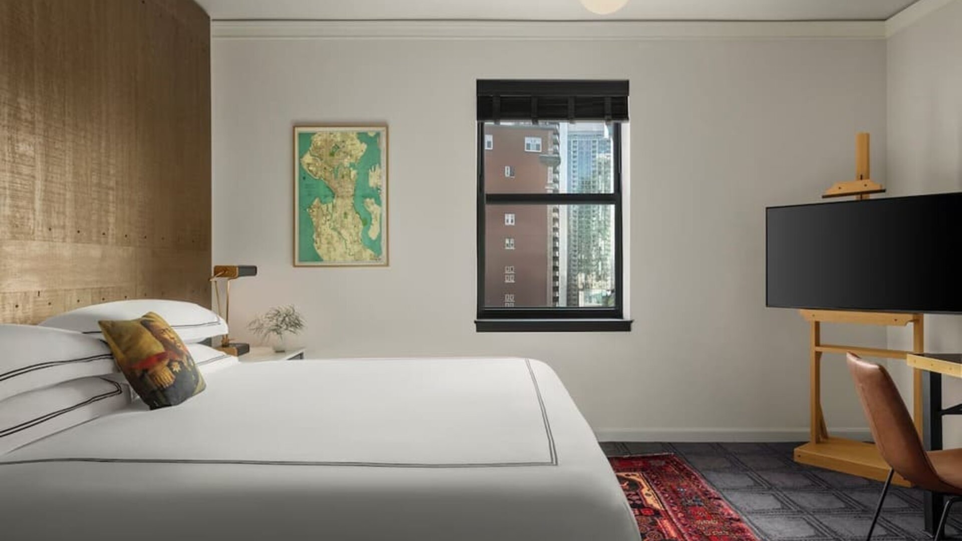 Bright bedroom with king bed, dual windows with city buildings, and framed artwork at Kimpton Palladian Hotel.