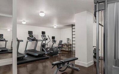 Fitness room with treadmills, weight bench, exercise ball, and mirrored wall at Kimpton Palladian Hotel.
