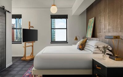 Bedroom with king bed, wood accent wall, desk, and city view window at Kimpton Palladian Hotel.
