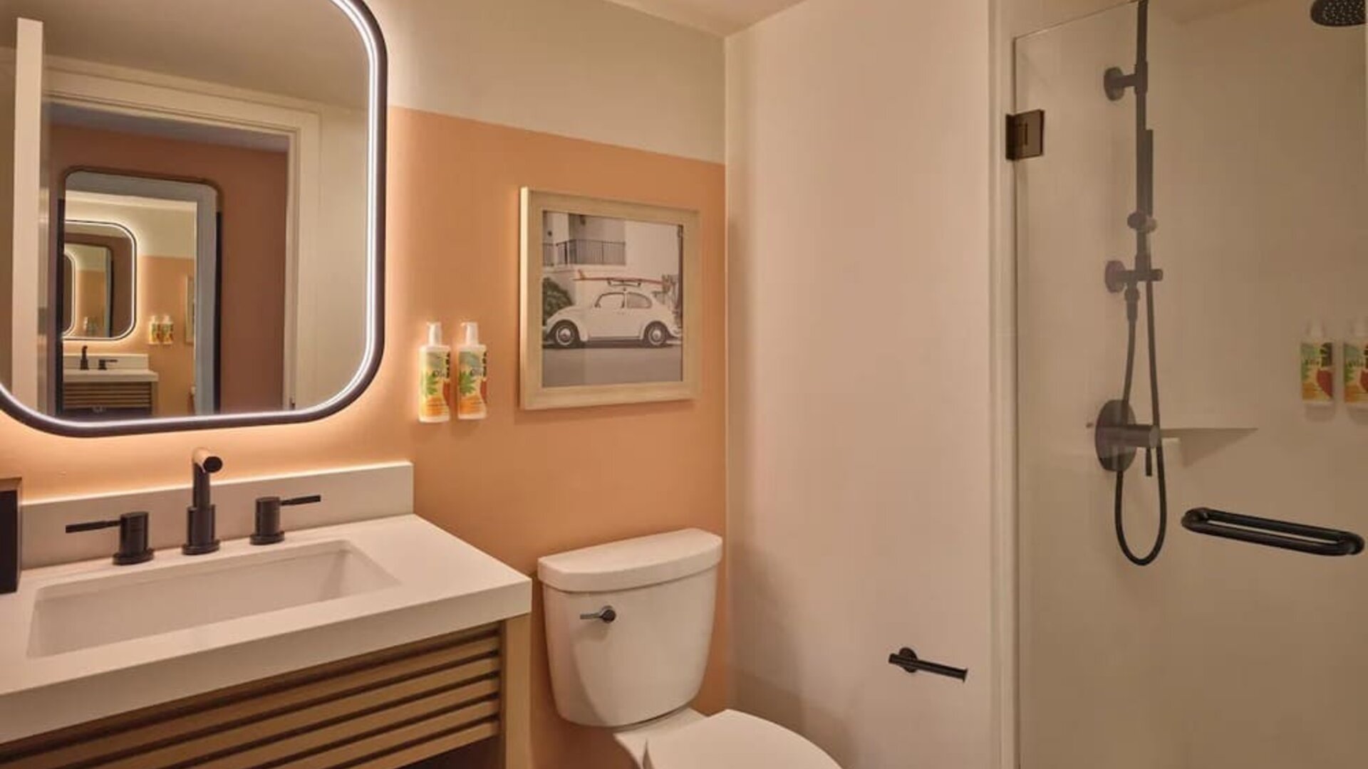 Modern bathroom with walk-in shower, illuminated mirror, and vanity at The Ambassador Hotel Of Waikiki.