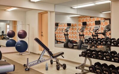 Gym area with free weights, bench, and exercise equipment at The Ambassador Hotel Of Waikiki.