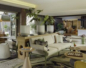 Lobby lounge with seating, indoor plants, and modern decor at The Ambassador Hotel Of Waikiki.