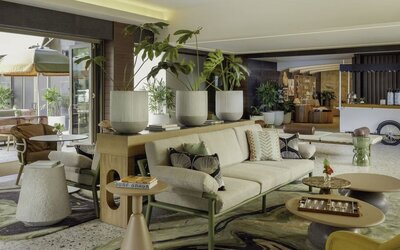 Lobby lounge with seating, indoor plants, and modern decor at The Ambassador Hotel Of Waikiki.
