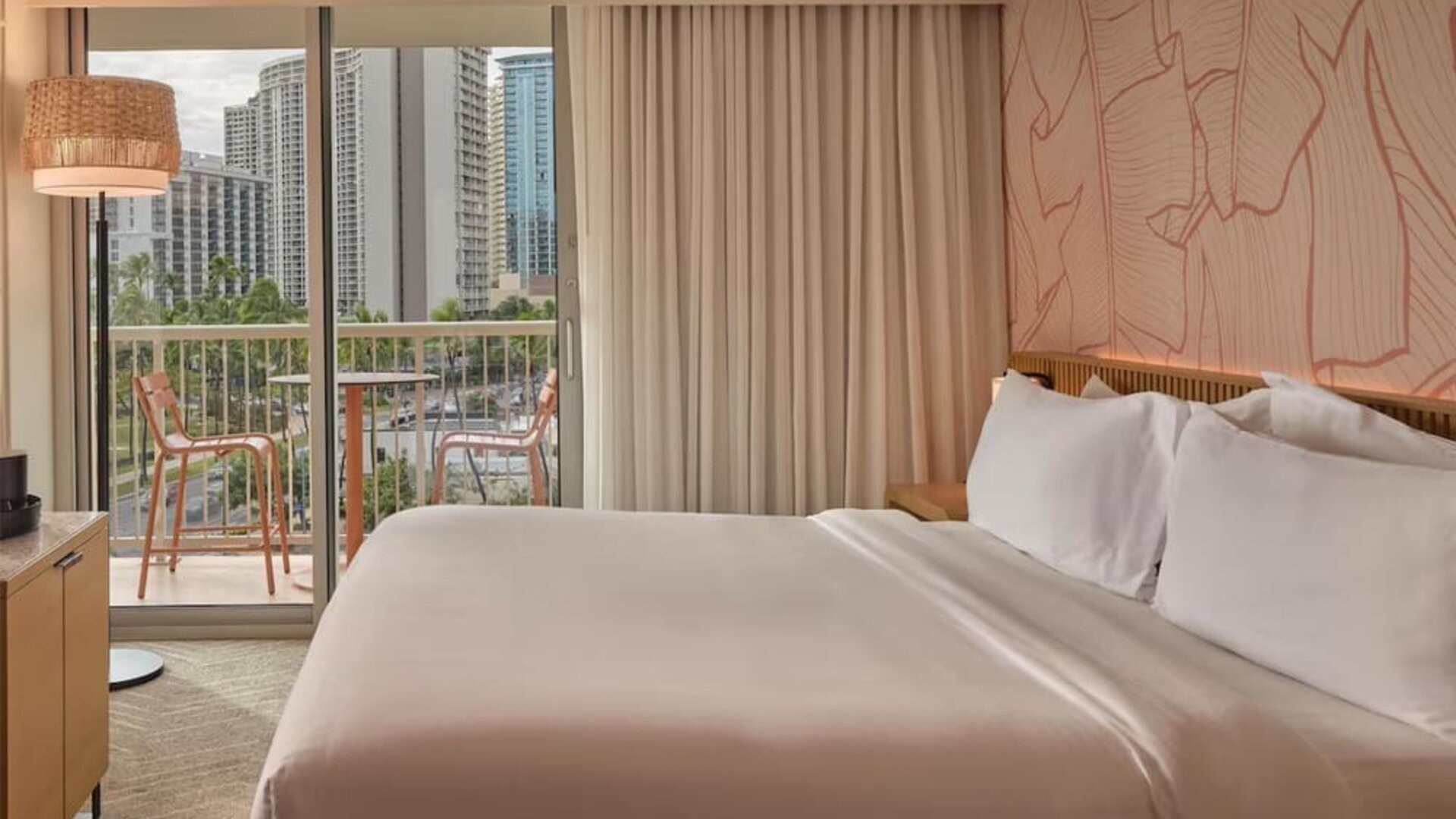 Guest room with king bed, balcony, and city skyline view at The Ambassador Hotel Of Waikiki.