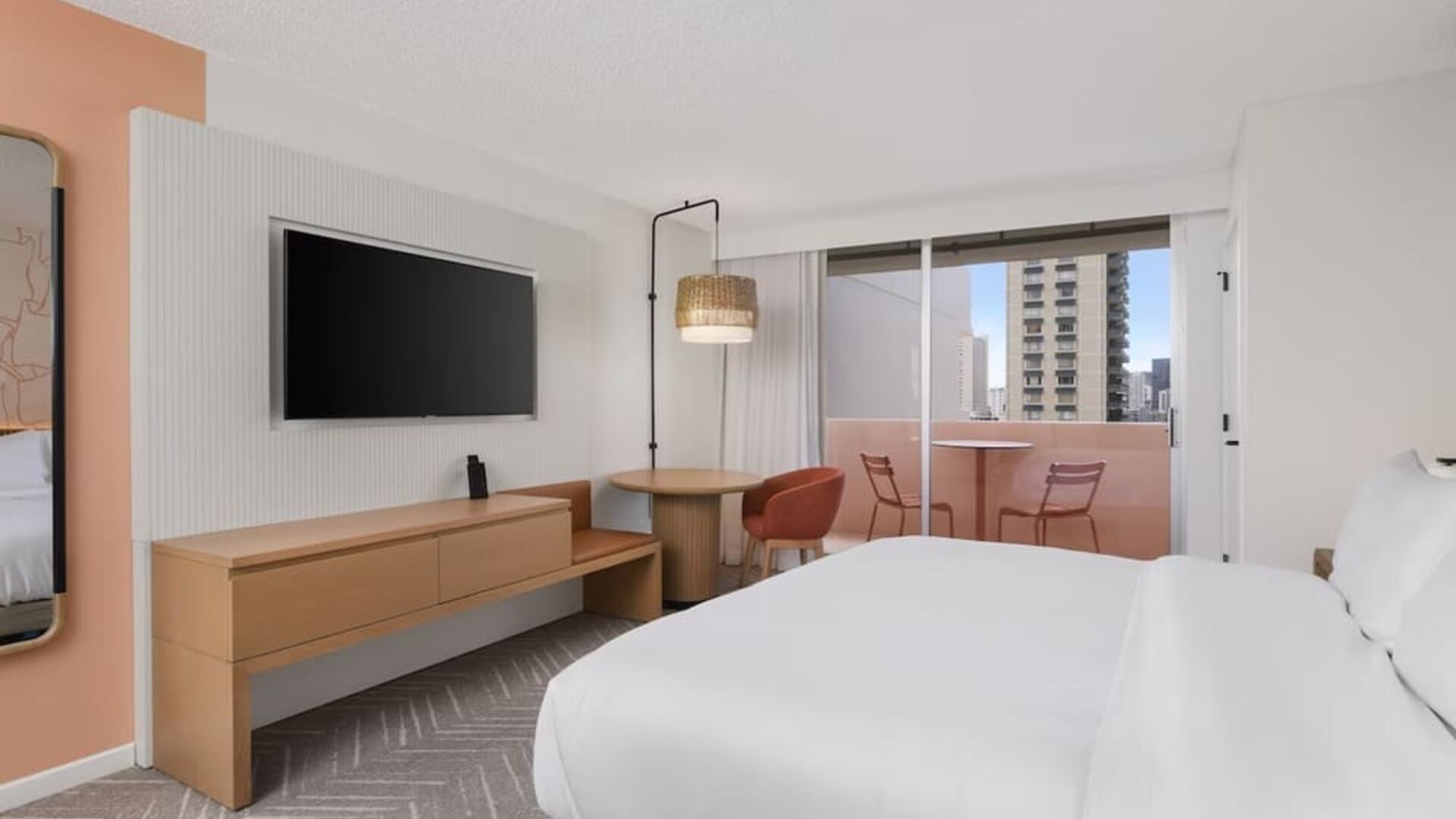 Guest room with balcony, seating area, and TV console at The Ambassador Hotel Of Waikiki.