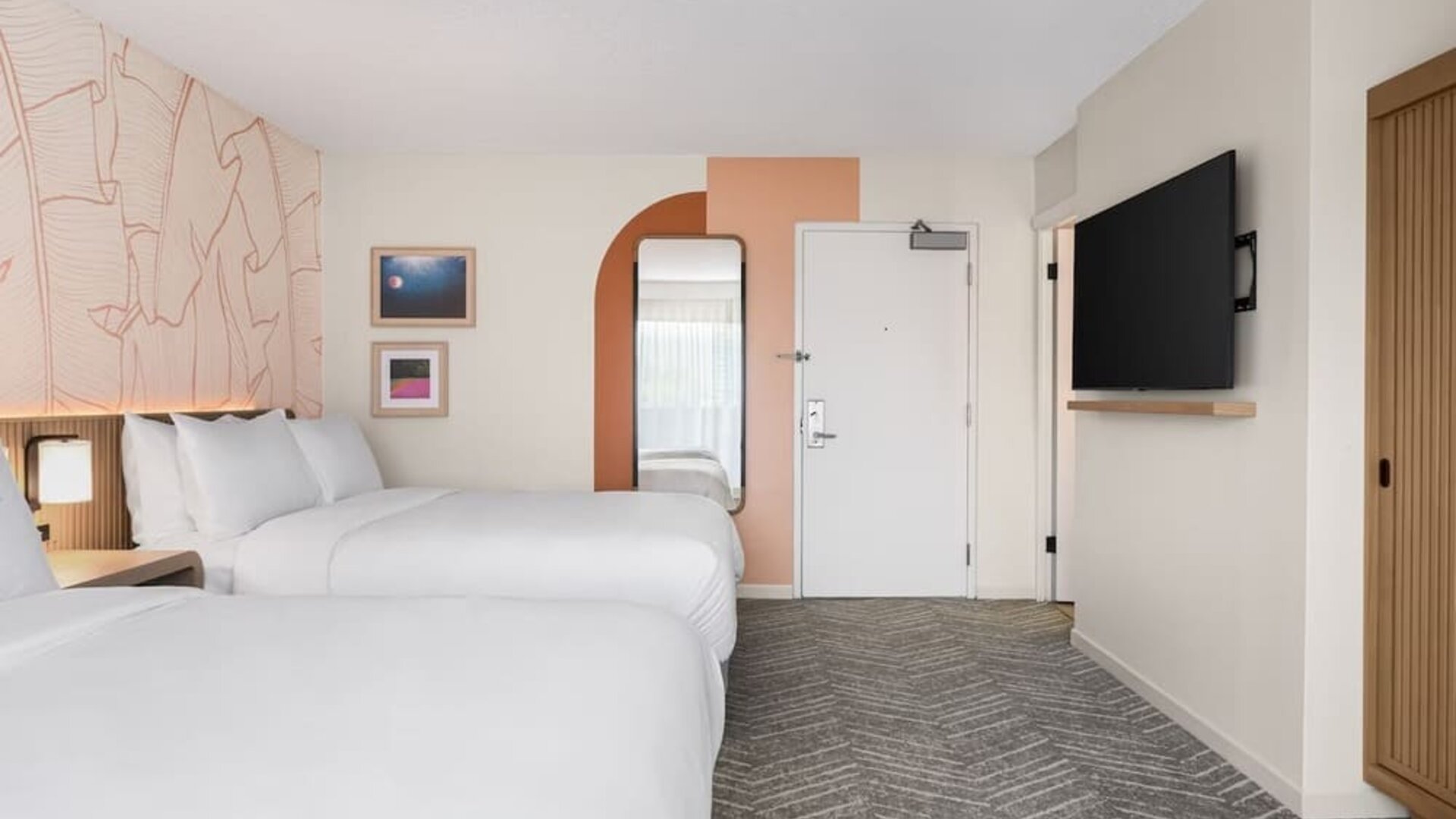 Guest room with two beds, wall-mounted TV, and minimalist decor at The Ambassador Hotel Of Waikiki.