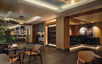 Reception lounge with warm lighting, wooden finishes, seating areas, and decorative ceiling fixtures at Romer House Waikiki