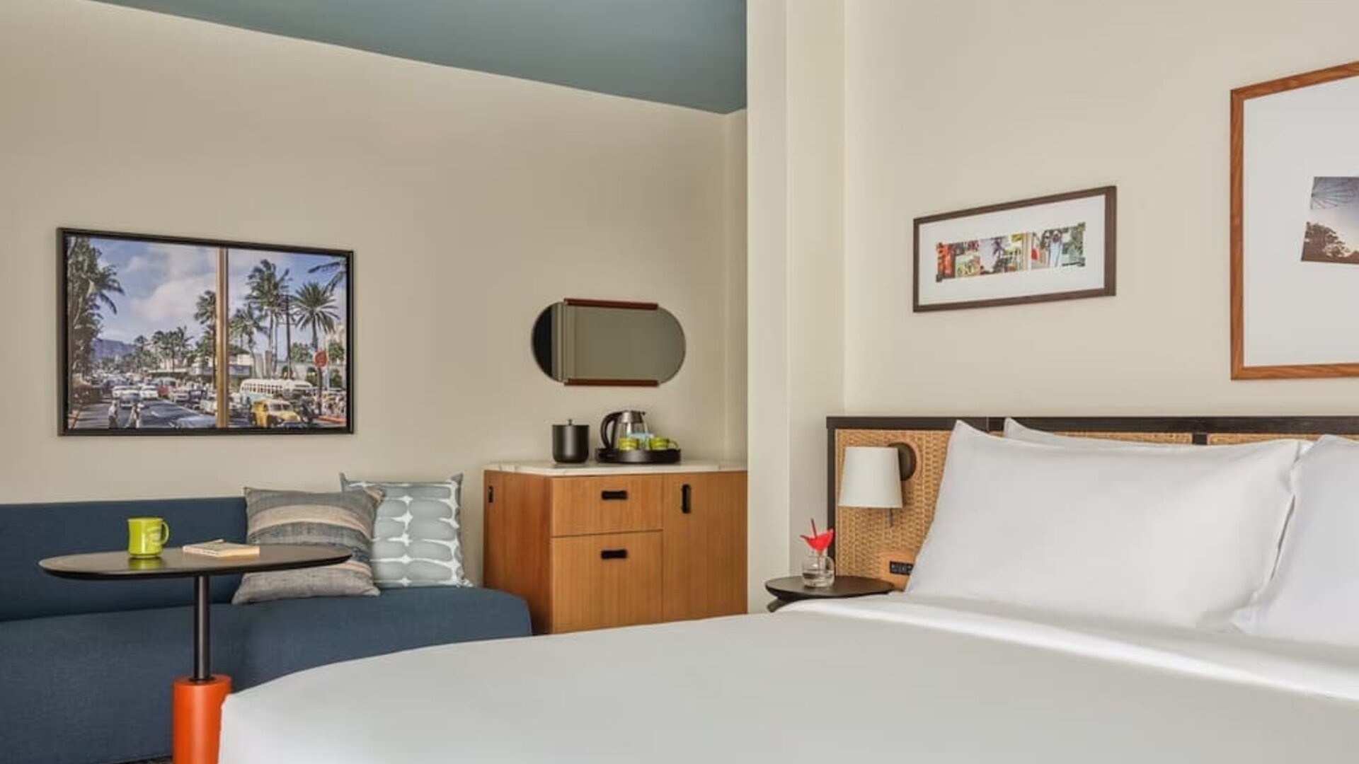 Blue sofa, round table, wooden cabinet, and wall art in a relaxed guest room at Romer House Waikiki.