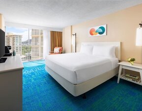 King bed room with balcony view, TV console, and mountain scenery in the distance at The Twin Fin Hotel.