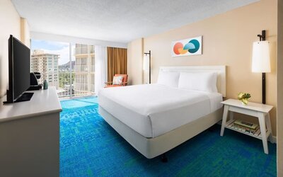 King bed room with balcony view, TV console, and mountain scenery in the distance at The Twin Fin Hotel.