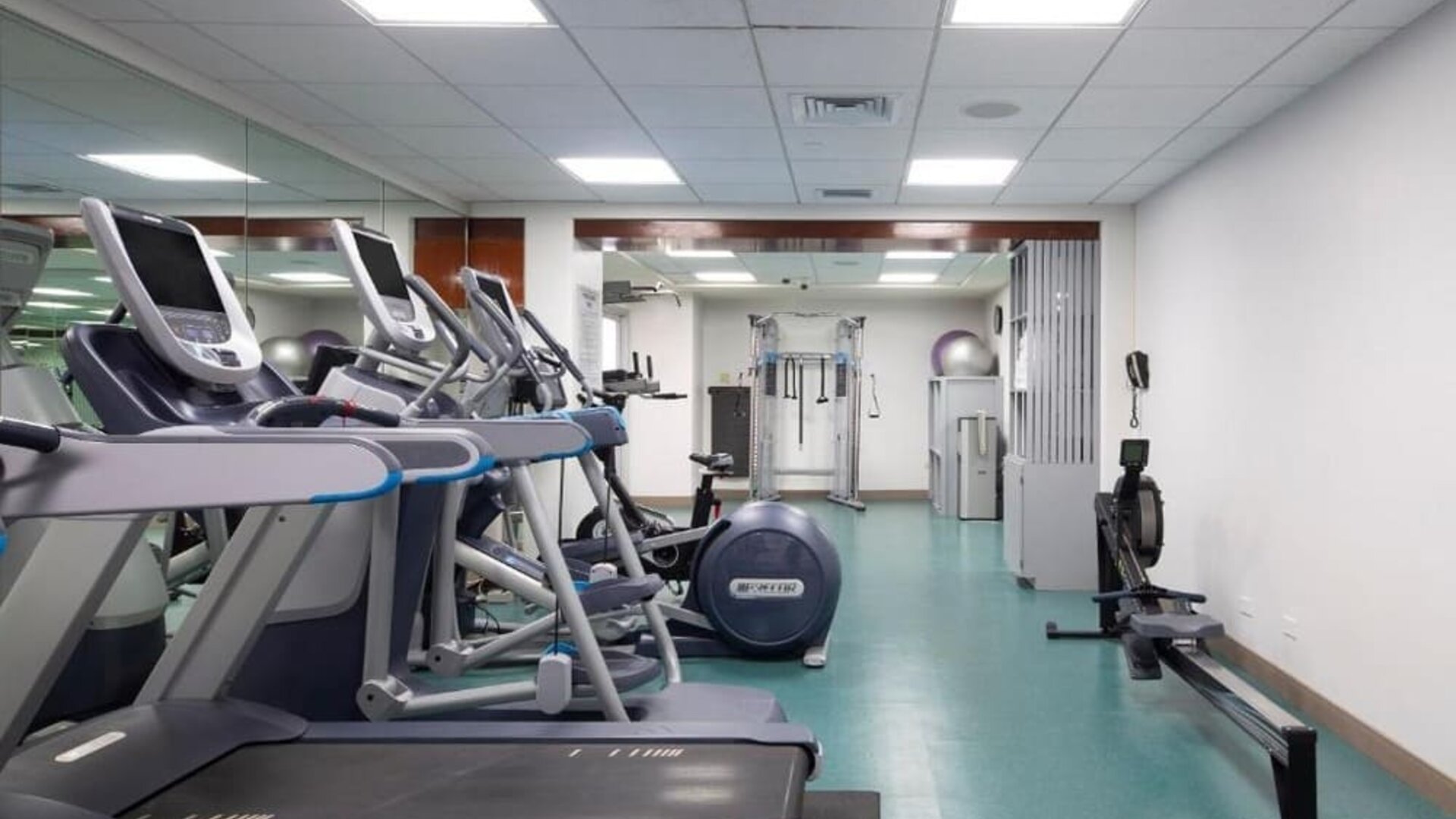 Gym with treadmills, rowing machine, and strength equipment in mirrored fitness room at The Twin Fin Hotel.