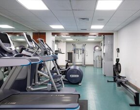 Gym with treadmills, rowing machine, and strength equipment in mirrored fitness room at The Twin Fin Hotel.