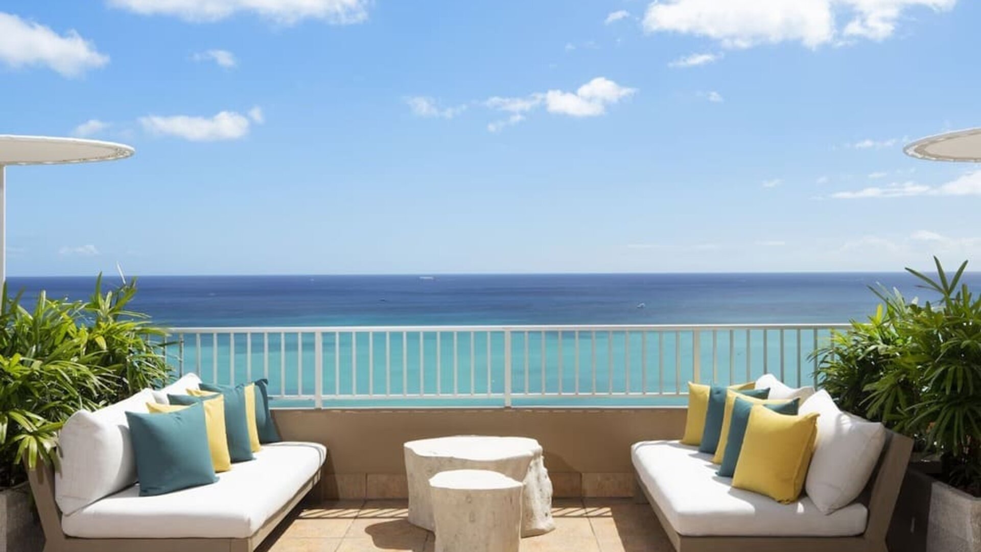 Outdoor seating area with ocean view, cushioned sofas, and umbrellas at The Twin Fin Hotel.