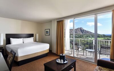 King bed room with balcony view of mountain and surrounding greenery at Park Shore Waikiki.