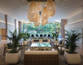 Spacious lobby with woven pendant lights, lounge seating, and large windows overlooking greenery at Park Shore Waikiki.