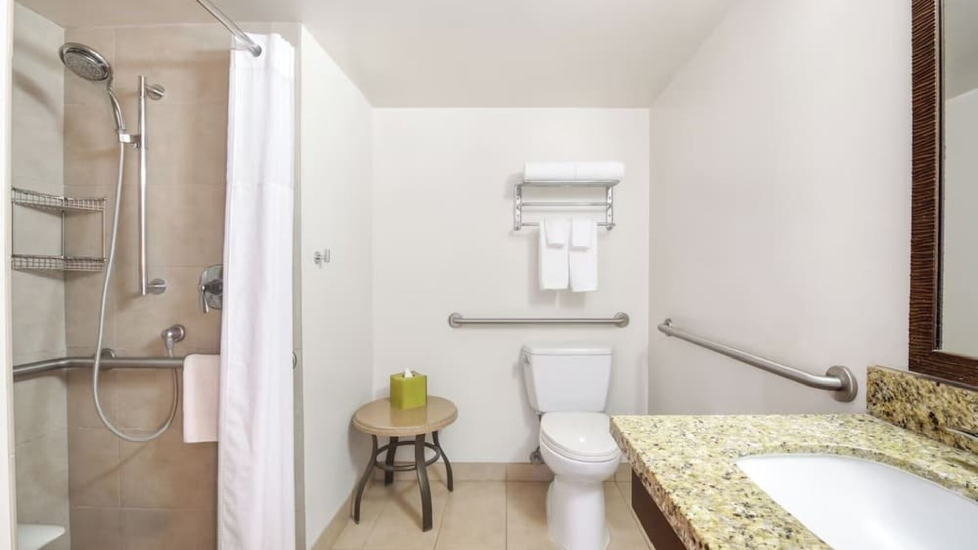 Accessible bathroom with walk-in shower, grab bars, toilet, and granite vanity at Park Shore Waikiki.