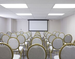 Meeting room with rows of chairs facing a presentation screen at Park Shore Waikiki.
