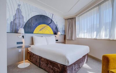 Bright double room with large bed, abstract mural headboard, and natural light from wide windows at Atlantic Tower Hotel Liverpool By Sunday.