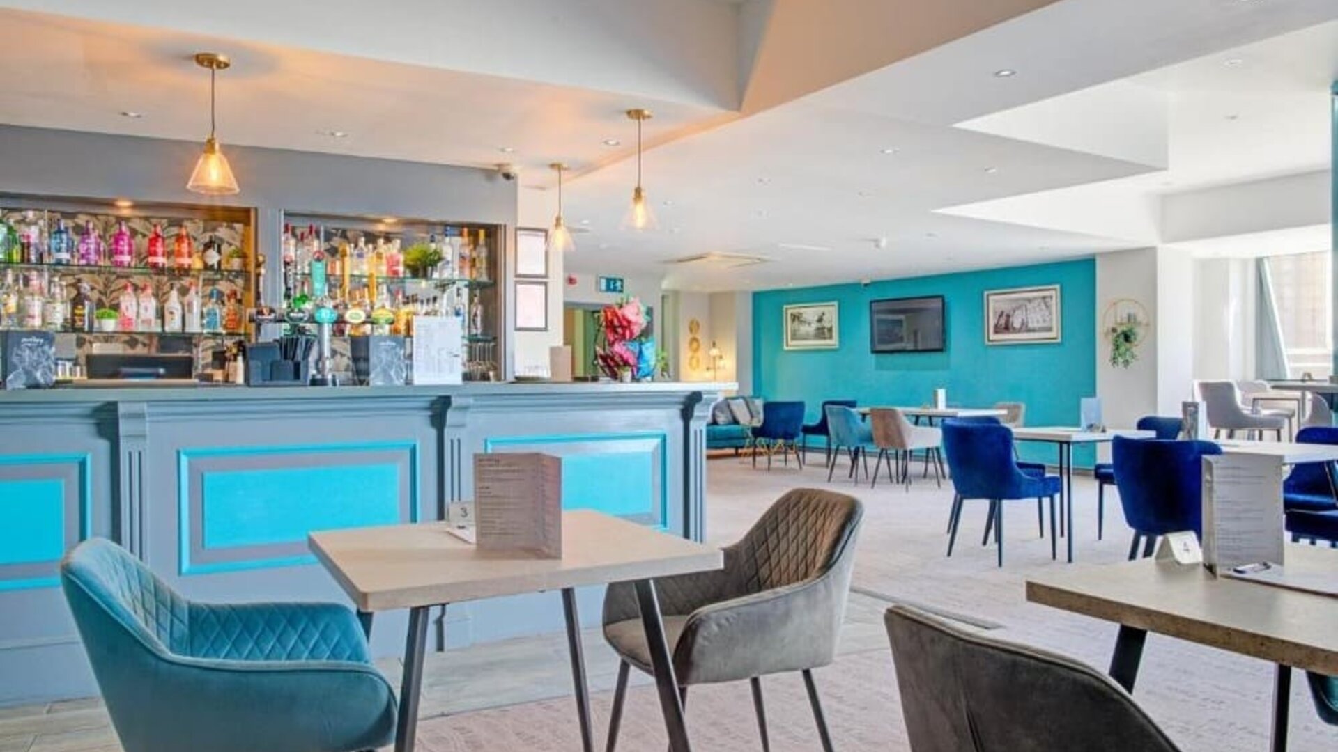 Stylish dining and bar area with blue accents, upholstered chairs, and pendant lighting at Atlantic Tower Hotel Liverpool By Sunday.