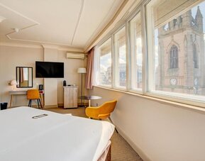 Guest room with large windows offering city views, workspace, and seating area at Atlantic Tower Hotel Liverpool By Sunday.