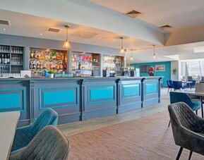 Hotel bar and dining space with long counter, seating area, and modern décor at Atlantic Tower Hotel Liverpool By Sunday.