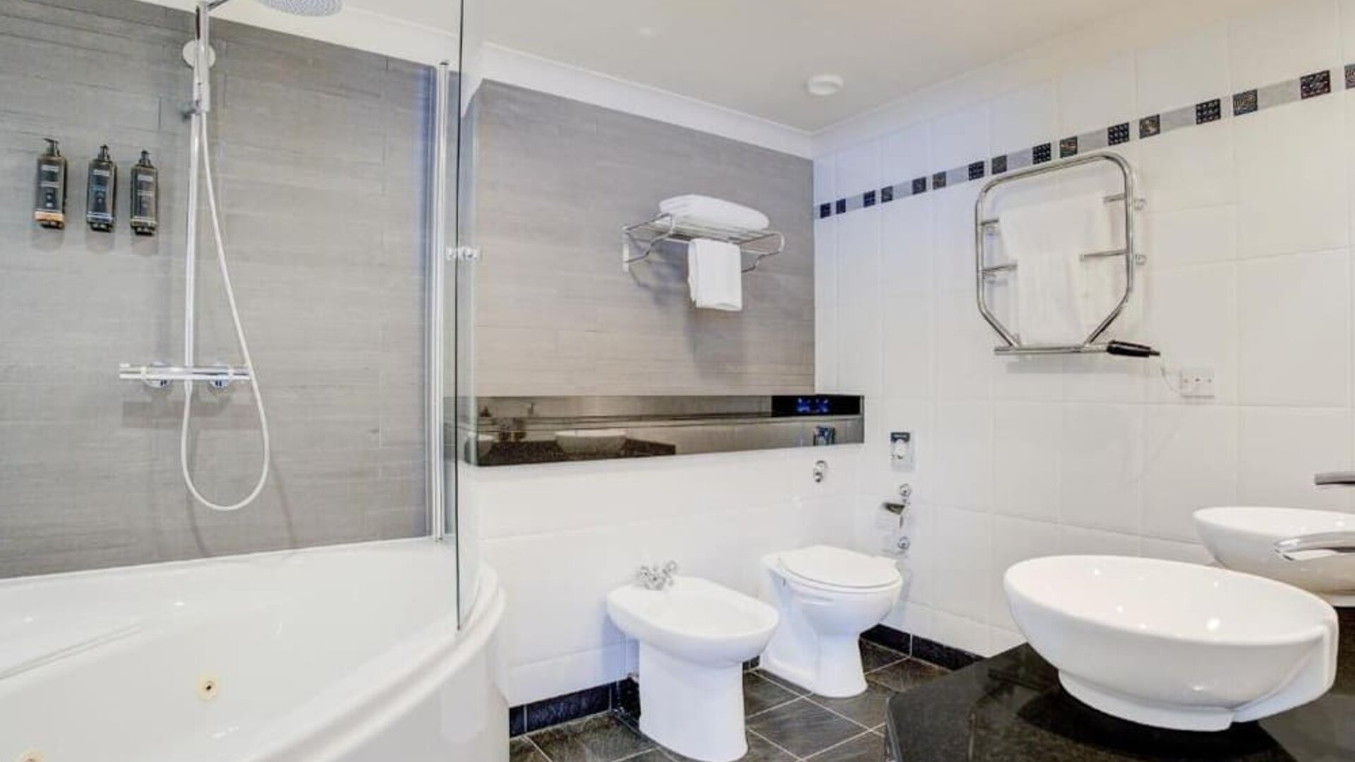 Large bathroom with bathtub, walk-in shower, bidet, and modern sink setup at Atlantic Tower Hotel Liverpool By Sunday.
