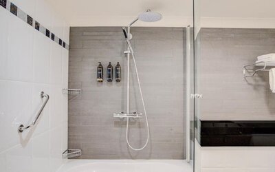 Bathroom with bathtub, rainfall shower, glass screen, and modern fixtures at Atlantic Tower Hotel Liverpool By Sunday.