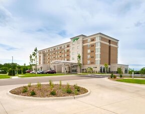 Exterior view of multi-story hotel building with driveway and landscaped entrance at Holiday Inn & Suites Farmington Hills - Detroit NW By IHG.