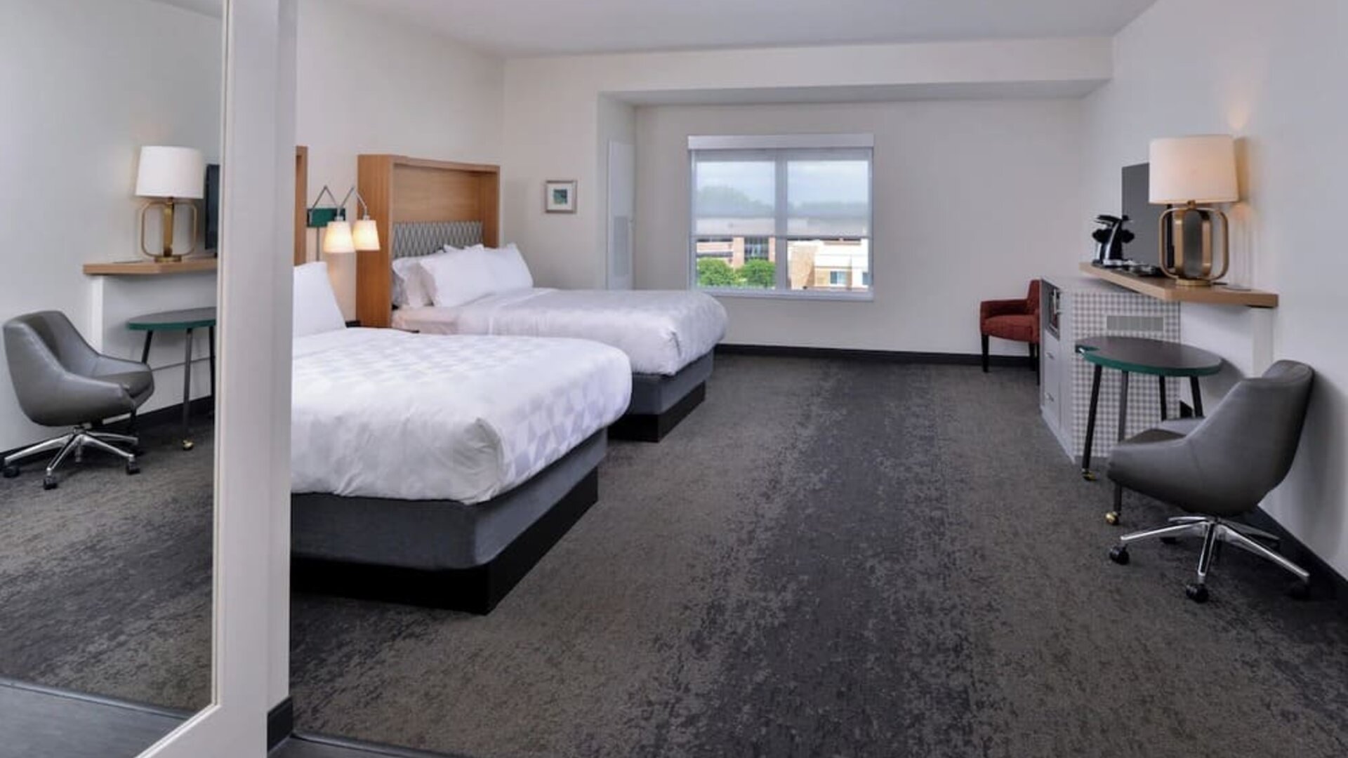 Double queen room with two beds, seating area, desk, and large window at Holiday Inn & Suites Farmington Hills - Detroit NW By IHG.