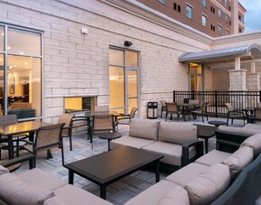 Outdoor seating area with cushioned sofas, tables, and covered entrance at Holiday Inn & Suites Farmington Hills - Detroit NW By IHG.