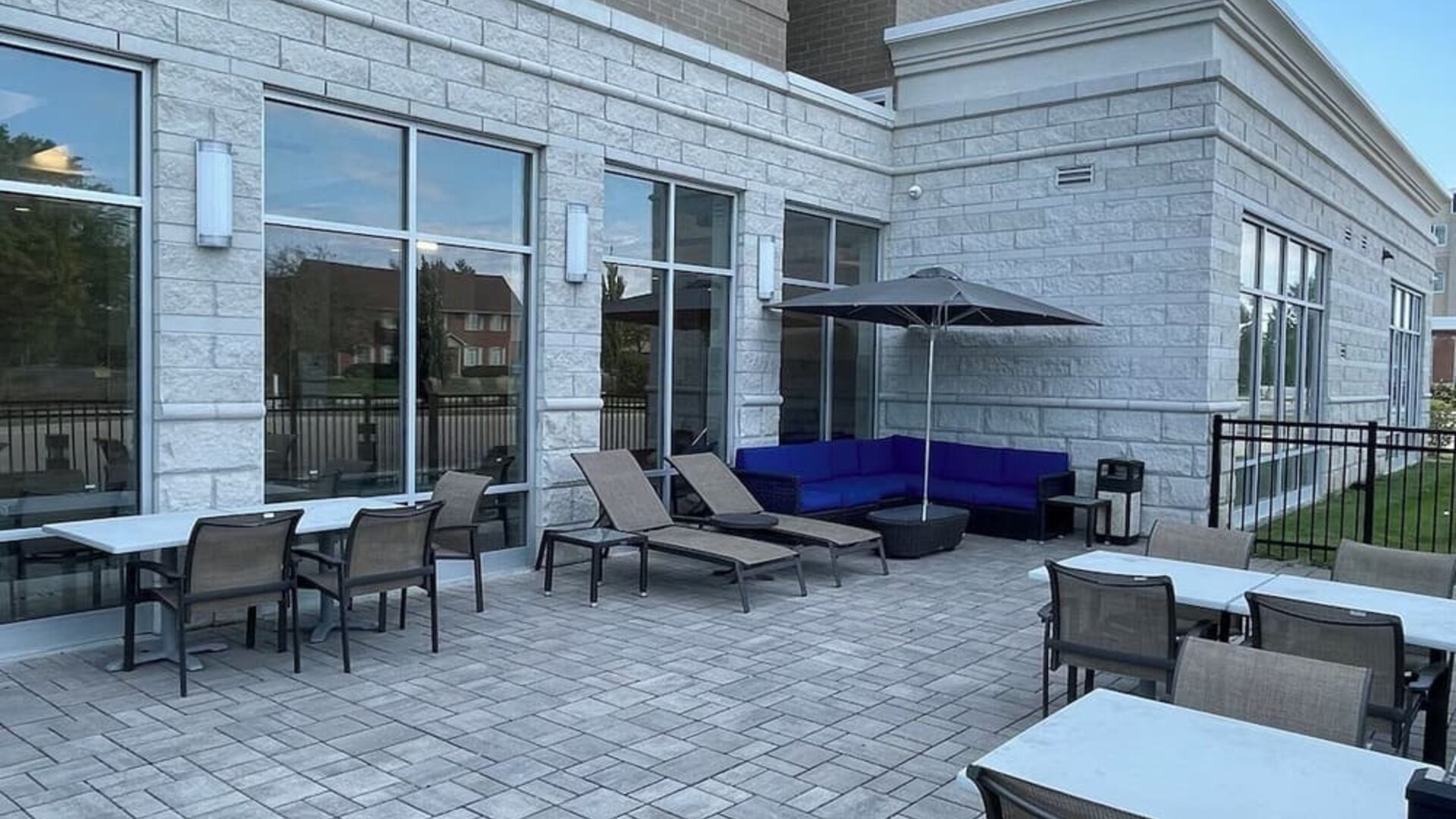 Outdoor patio with lounge chairs, umbrella seating, and paved terrace at Holiday Inn & Suites Farmington Hills - Detroit NW By IHG.