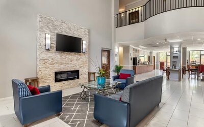 Lobby seating area with armchairs, coffee table, fireplace wall, and open layout at Comfort Suites Bush Intercontinental Airport.