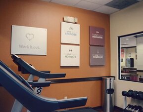 Fitness room with treadmill, dumbbells, wall mirror, and motivational wall signs at Comfort Suites Bush Intercontinental Airport