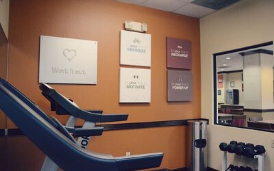 Fitness room with treadmill, dumbbells, wall mirror, and motivational wall signs at Comfort Suites Bush Intercontinental Airport