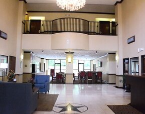 Lobby with high ceiling, chandelier, seating area, and reception desk in an open space at Comfort Suites Bush Intercontinental Airport.
