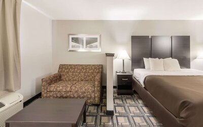 King room with sofa seating, coffee table, bedside lamps, and window with curtains at Suburban Studios Mason Hwy-42.