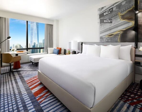 King room with large bed, city skyline view, seating area, desk, and modern décor at M Social New York Downtown.