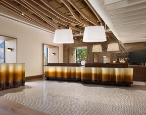 Lobby area with reception desk, modern lighting fixtures, and stylish interior design at M Social New York Downtown.