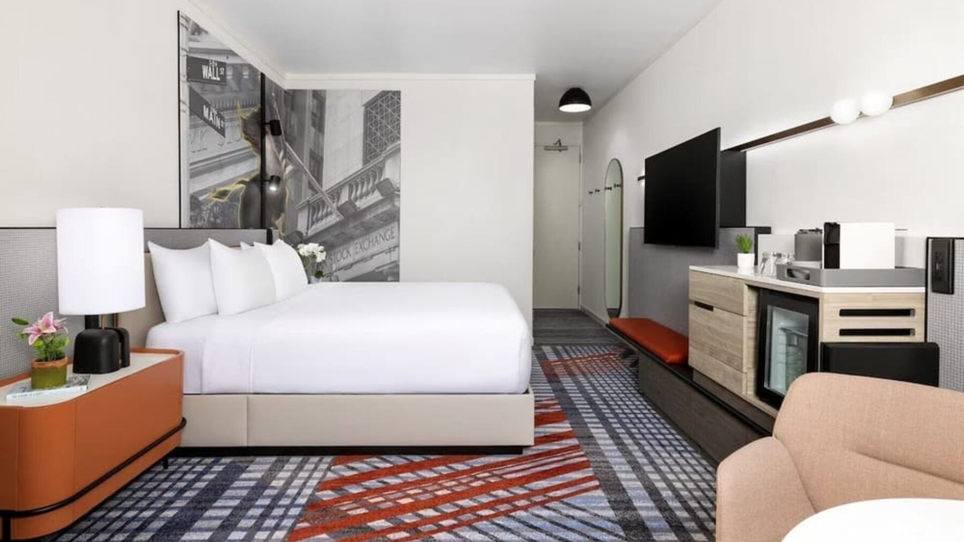 Guest room with king bed, mini fridge, coffee station, wall art, and modern furnishings at M Social New York Downtown.