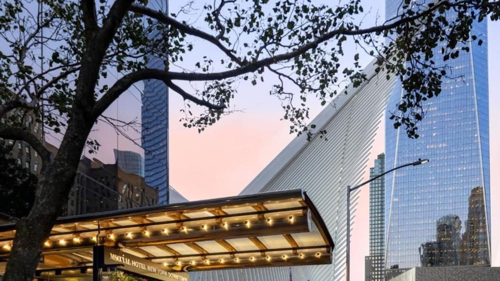 Hotel exterior entrance with covered canopy and surrounding city architecture at M Social New York Downtown.