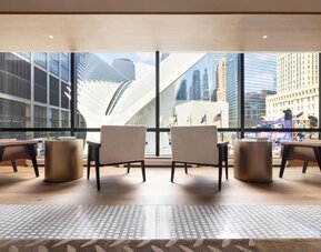 Seating area with large windows overlooking city architecture and natural light-filled space at M Social New York Downtown.
