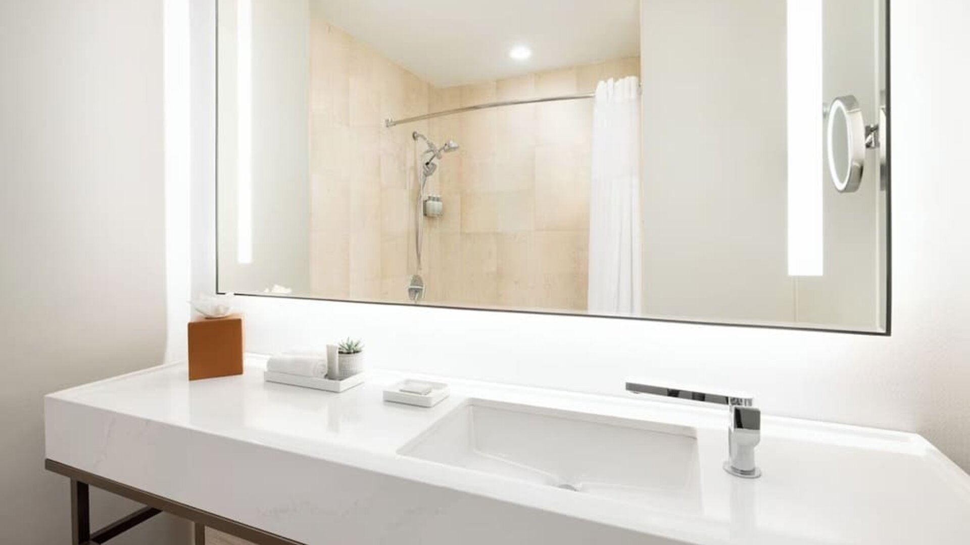 Modern bathroom with large mirror, vanity sink, walk-in shower, and neatly arranged amenities at M Social New York Downtown.