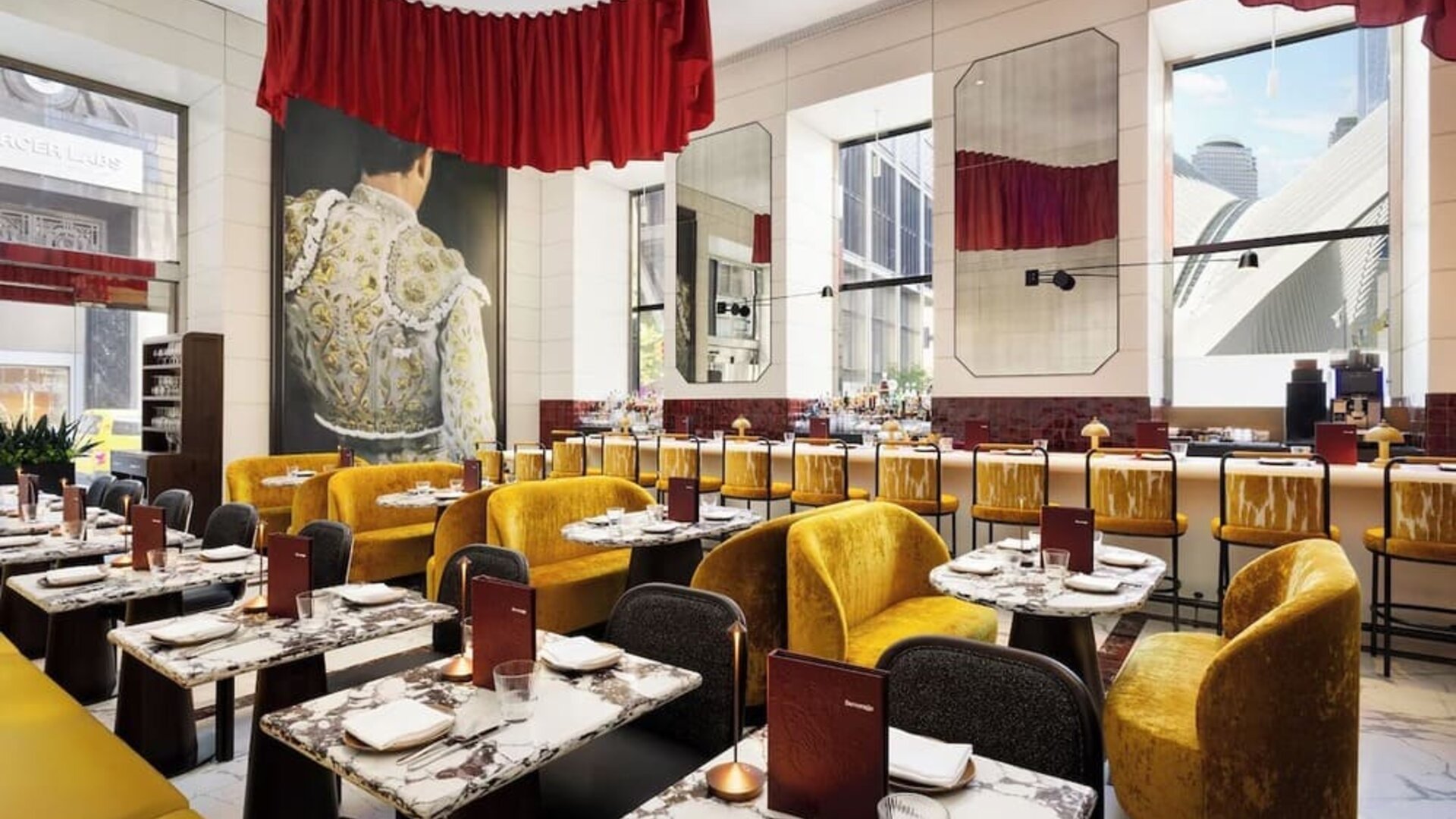 Restaurant dining area with marble tables, red accents, gold seating, and statement artwork at M Social New York Downtown.