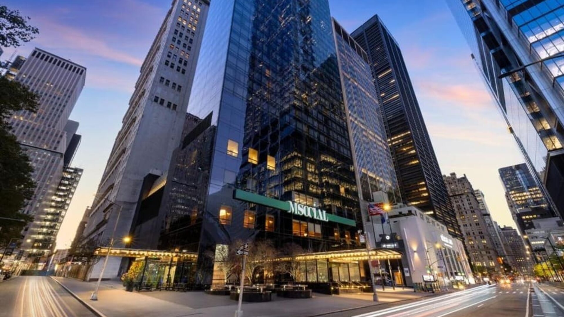 Exterior view of the hotel building surrounded by tall skyscrapers and city streets at M Social New York Downtown.