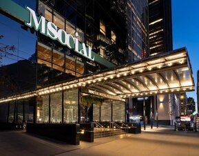 Hotel exterior entrance with illuminated canopy, glass façade, and city street view at M Social New York Downtown.