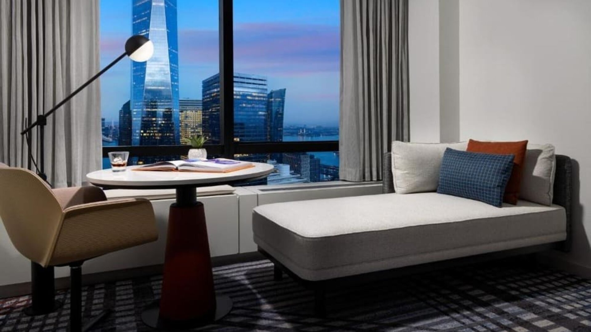 Lounge seating area with city skyline view at dusk through large windows at M Social New York Downtown.